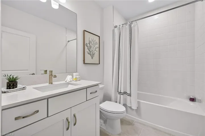 Bathroom with vanity, shower / bath combo, and light tile patterned floors