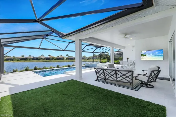 View of pool with a water view, a yard, a lanai, ceiling fan, and a patio area