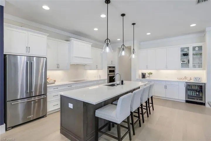 Kitchen with wine cooler, stainless steel appliances, and white cabinetry