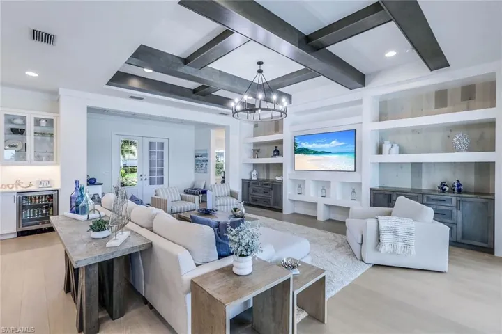 Living room featuring built in features, beam ceiling, french doors, beverage cooler, and light hardwood / wood-style floors