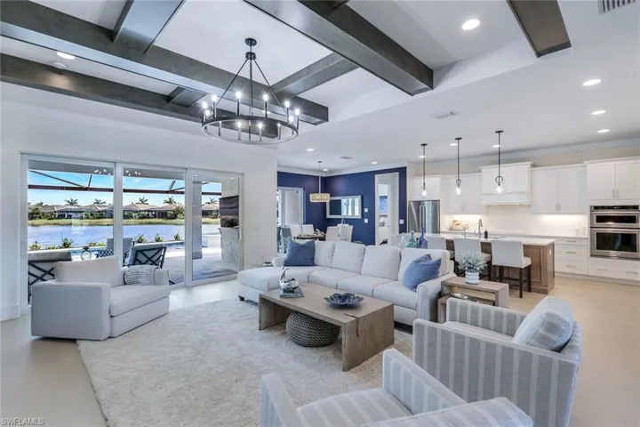 Living room featuring a water view, sink, beamed ceiling, and a chandelier