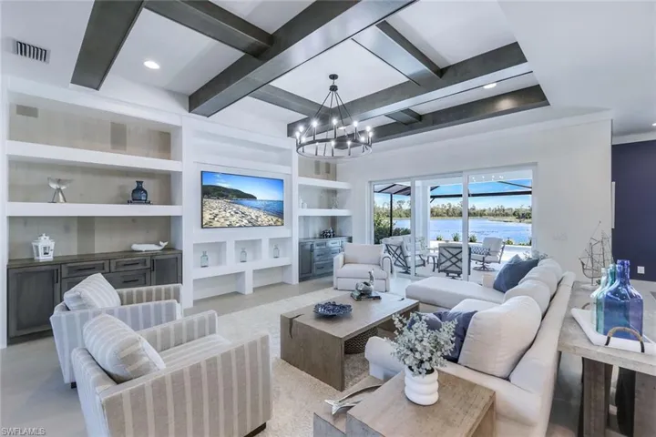 Living room with a chandelier, beamed ceiling, and built in features