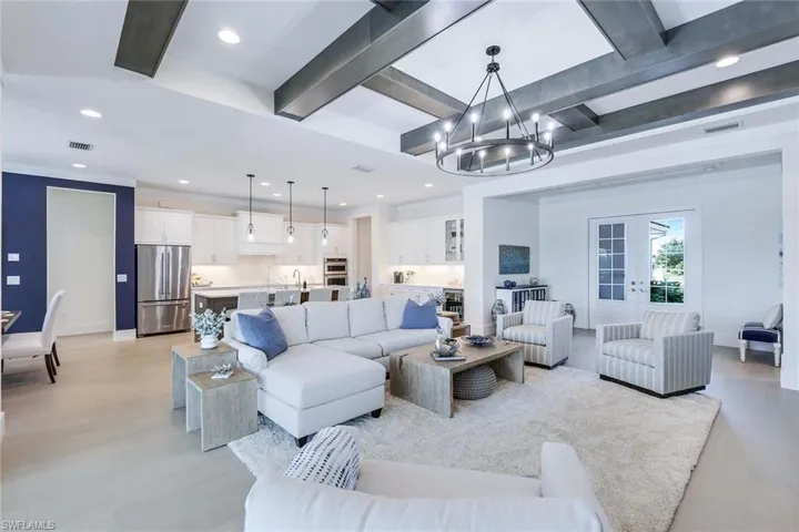 Living room featuring light hardwood / wood-style floors, beam ceiling, and an inviting chandelier