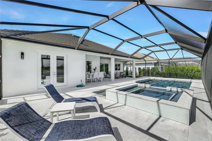 View of pool with a lanai, a patio, an in ground hot tub, and french doors