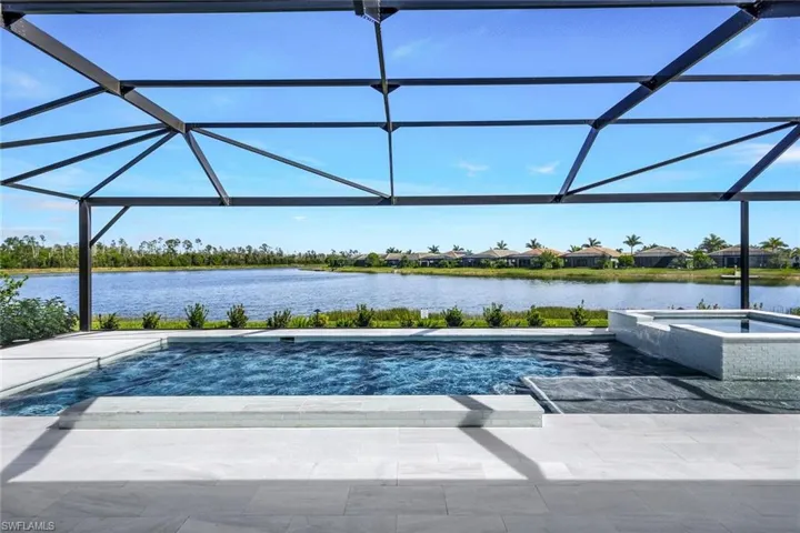 View of pool featuring a lanai, a patio, an in ground hot tub, and a water view