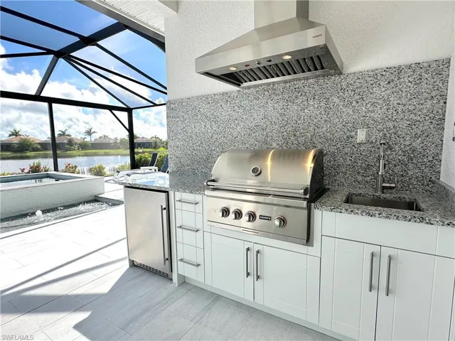 View of patio / terrace featuring area for grilling, sink, a grill, a lanai, and a water view