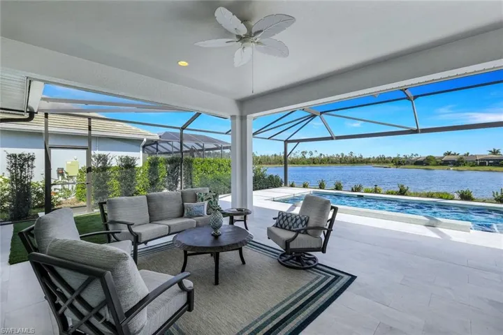 View of patio with glass enclosure, a water view, outdoor lounge area, and ceiling fan