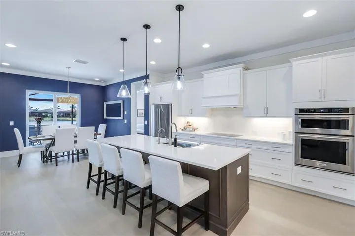 Kitchen with white cabinetry, pendant lighting, stainless steel appliances, and an island with sink