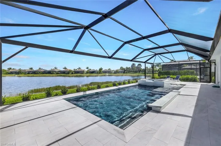 View of swimming pool featuring a water view, glass enclosure, an in ground hot tub, and a patio area