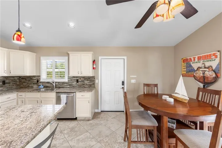 Kitchen featuring stainless steel dishwasher, white cabinetry, light stone countertops, pendant lighting, and recessed lighting