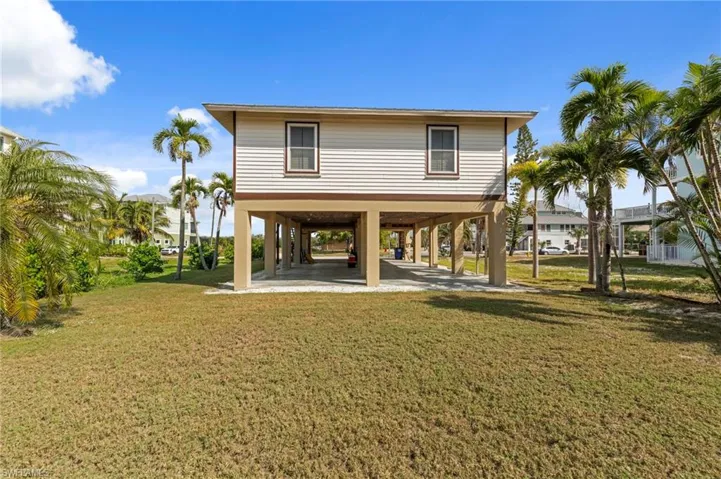 Back of house with a carport, a yard, and a patio