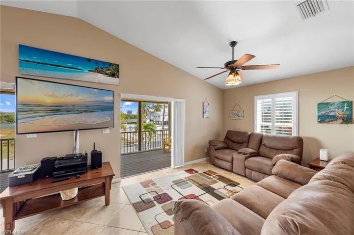 Living room with lofted ceiling, a ceiling fan, and light tile patterned floors