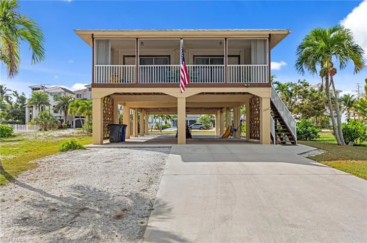 Raised beach house featuring a carport, driveway, and stairway