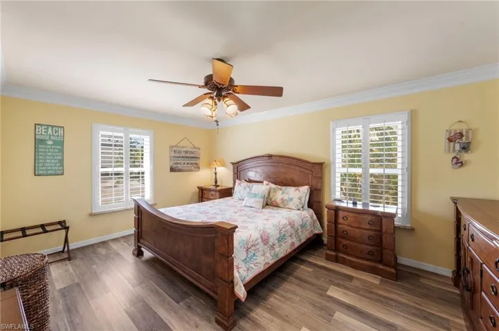 Bedroom with ornamental molding, wood finished floors, multiple windows, and ceiling fan