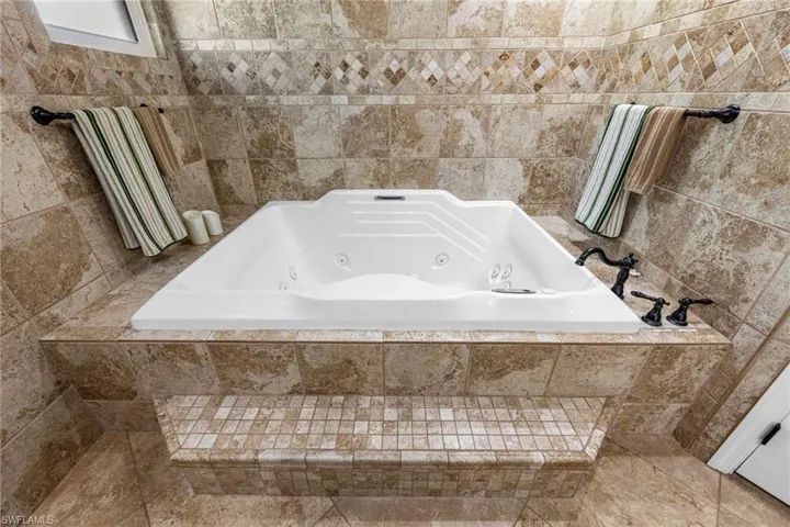 Full bath with a whirlpool tub and tile walls