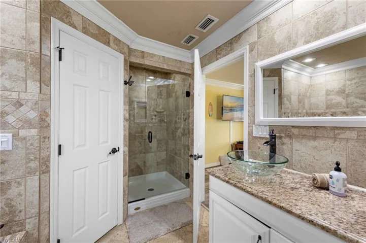 Bathroom with ornamental molding, vanity, and a shower stall