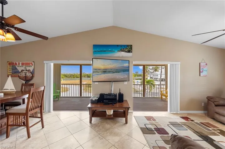 Living room with a ceiling fan, vaulted ceiling, plenty of natural light, and light tile patterned floors