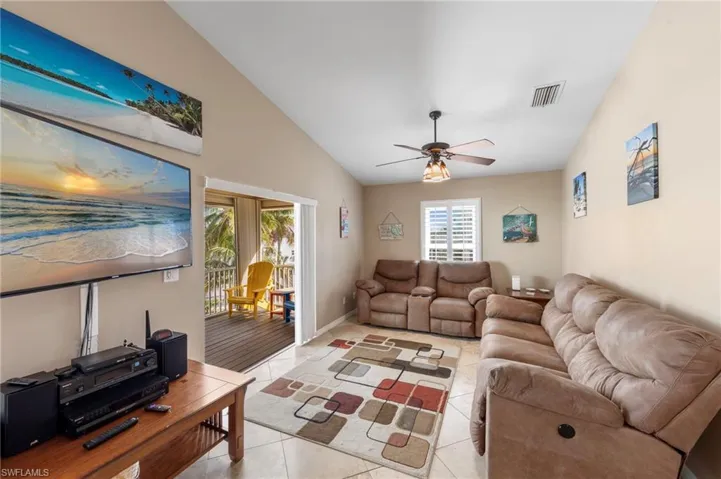 Living area featuring lofted ceiling, light tile patterned flooring, and a ceiling fan