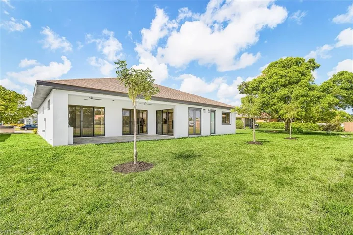 Expansive rear yard featuring a manicured lawn and mature trees