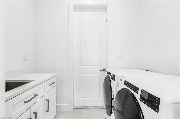 Utility room featuring white cabinetry, a light-toned countertop, and a stainless steel sink
