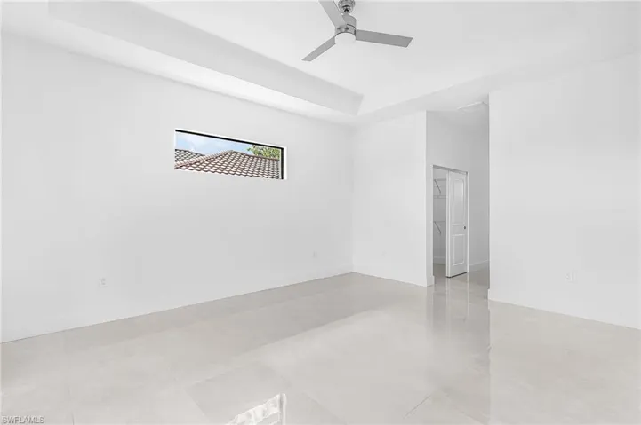 Spacious room featuring light-toned tile flooring, white walls, and a contemporary ceiling fan