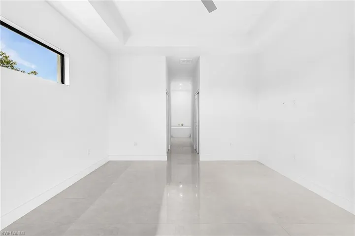 Spacious interior room featuring light-toned tile flooring and crisp white walls