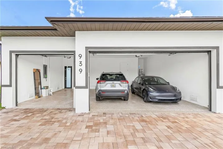 Modern exterior featuring a two-bay garage with contemporary gray trim, a durable paved driveway, and a secure side entry door
