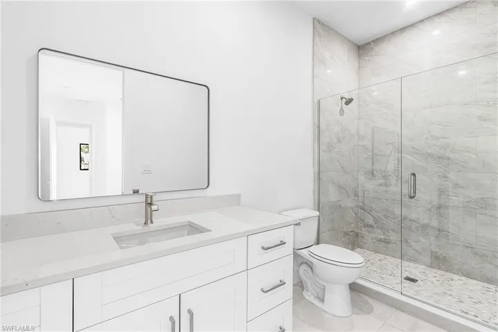 Modern bathroom featuring a glass-enclosed shower with gray tiled walls and flooring