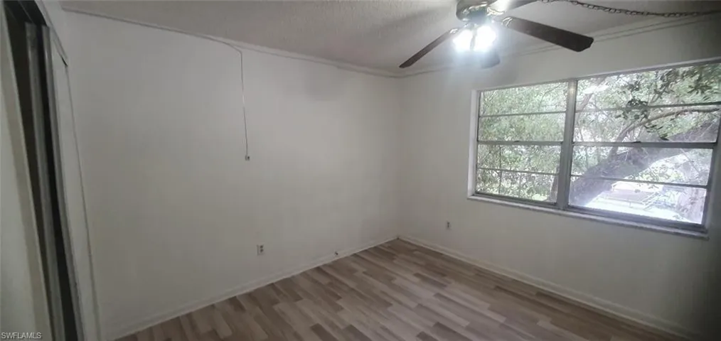 Spare room with light wood finished floors, a textured ceiling, and ceiling fan