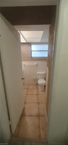 Bathroom with wallpapered walls and light tile patterned flooring