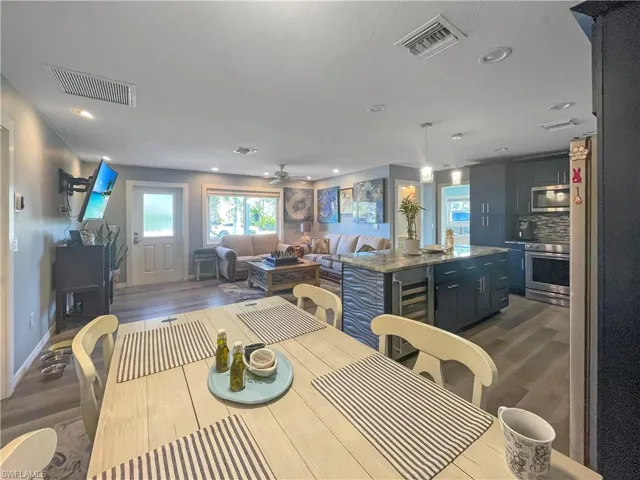 Dining room featuring dark wood-style flooring, wine cooler, ceiling fan, and recessed lighting