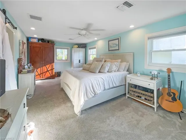 Bedroom featuring a barn door, light carpet, a ceiling fan, recessed lighting, and a closet
