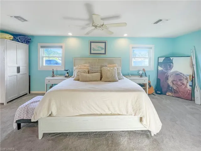 Carpeted bedroom with a ceiling fan, multiple windows, and recessed lighting