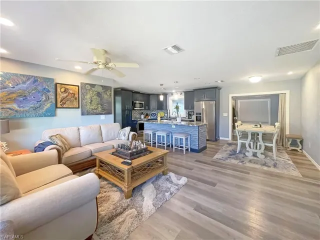 Living room featuring dark wood finished floors, ceiling fan, and recessed lighting