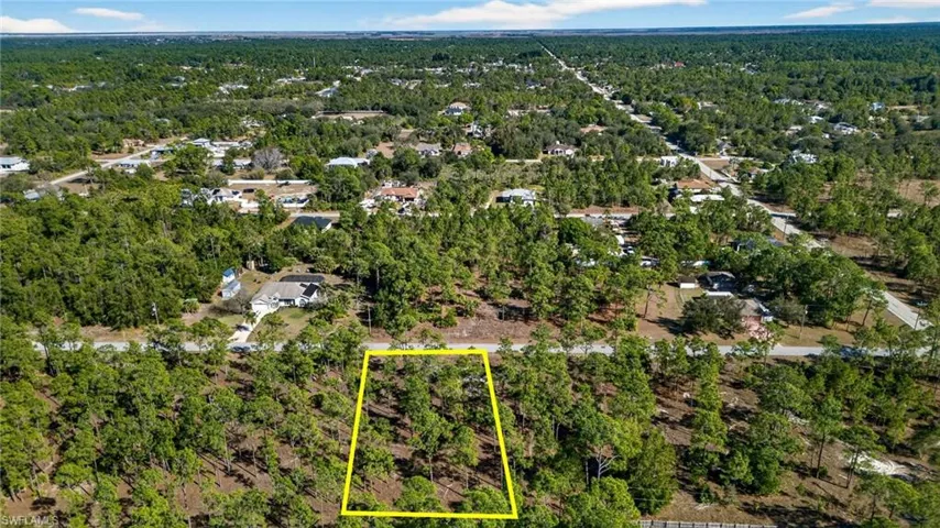 Aerial view of property and surrounding area featuring a forest and property parcel outlined