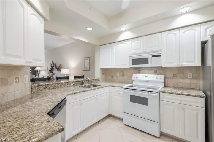 Kitchen with appliances with stainless steel finishes, white cabinetry, decorative backsplash, and recessed lighting