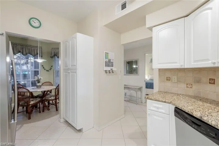 Kitchen featuring light stone counters, appliances with stainless steel finishes, white cabinetry, and light tile patterned flooring