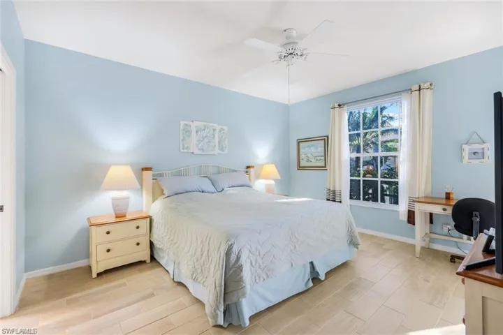 Bedroom with wood finish floors, ceiling fan, and an office area