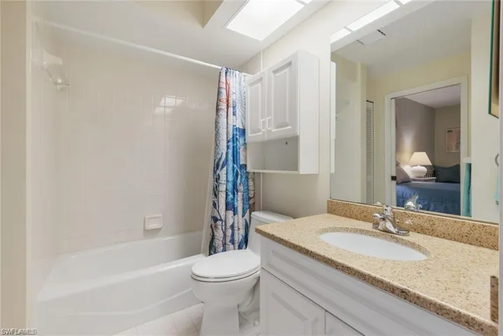 Full bathroom with shower / tub combo with curtain, vanity, a skylight, and ensuite bathroom