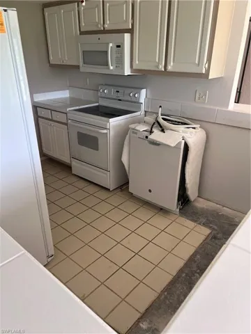 Kitchen with light tile patterned floors and white appliances