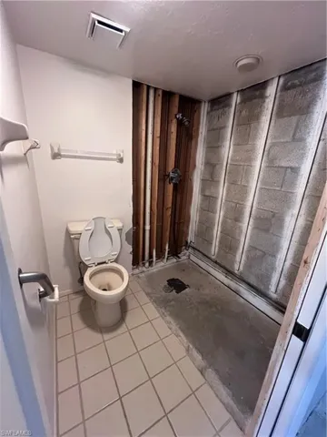 Bathroom featuring toilet, tile patterned floors, and walk in shower