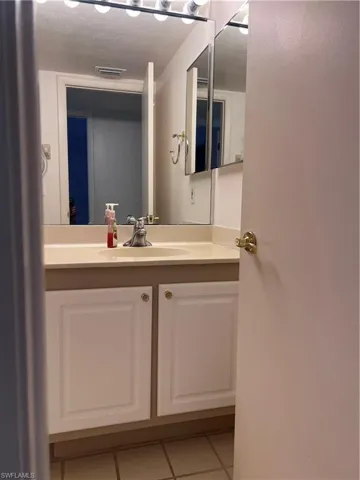 Bathroom with tile patterned flooring, a textured ceiling, and vanity