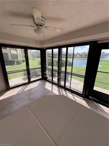 Unfurnished sunroom featuring ceiling fan and a water view