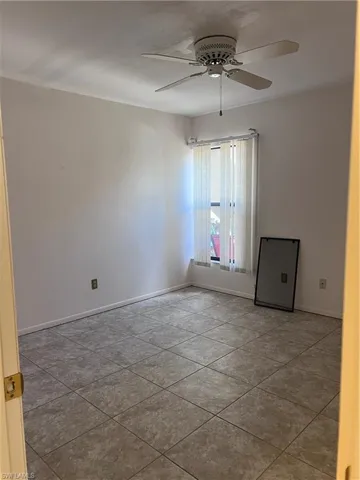 Tiled spare room featuring ceiling fan
