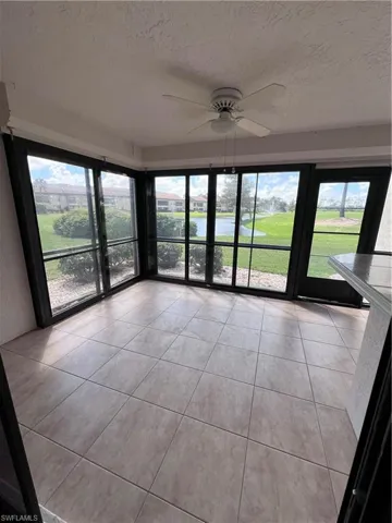 Tiled empty room featuring ceiling fan, a wealth of natural light, and a textured ceiling