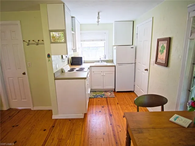Cottage Kitchen: electric range/oven, fridge, built in cabinets, window over sink overlooking flowers