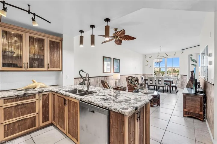 Kitchen featuring sink, stainless steel dishwasher, ceiling fan, light tile patterned floors, and kitchen peninsula
