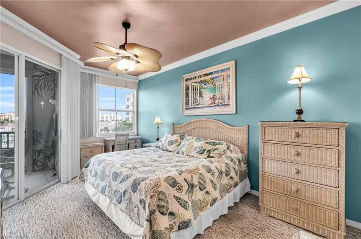 Carpeted bedroom featuring ceiling fan, access to exterior, and ornamental molding