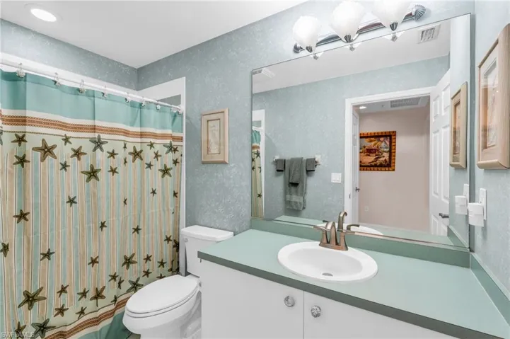 Bathroom with vanity, curtained shower, and toilet