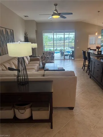 Living room featuring light tile patterned floors, vaulted ceiling, and ceiling fan